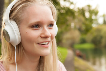 young girl in white headphones listening to music, walking with headphones, listening to music