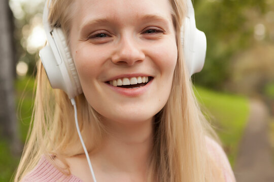 young girl in white headphones listening to music, walking with headphones, listening to music