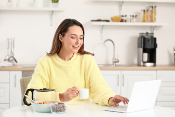Morning of beautiful woman with laptop drinking coffee at home