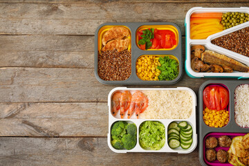 Containers with different tasty food on wooden background