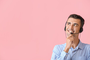 Thoughtful male consultant of call center with headset on pink background