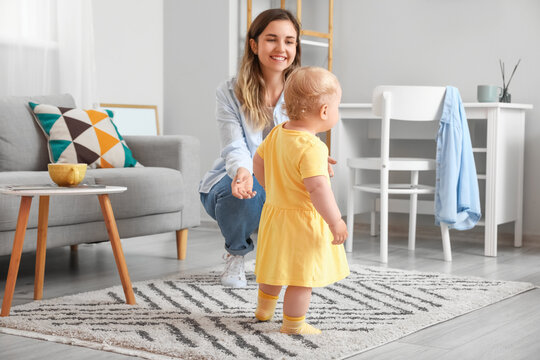 Cute Baby Girl In Yellow Dress Learning To Walk With Mother At Home