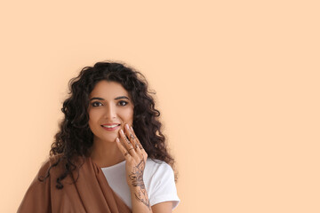 Beautiful Indian woman with henna tattoo on color background