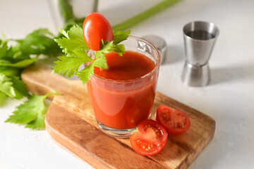 Board with glass of bloody mary on light background