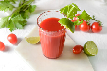 Board with glass of bloody mary on light background