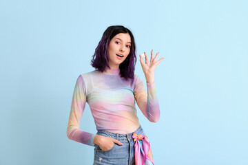 Stylish young woman with purple hair holding chewing gums on blue background