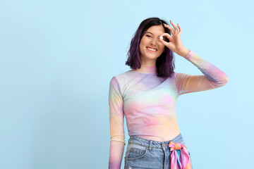 Stylish young woman with purple hair holding chewing gum on blue background