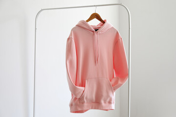 Rack with hoodie near light wall