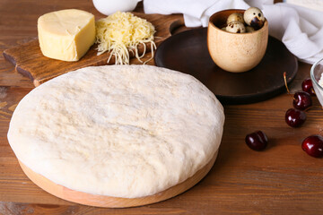 Fresh dough and ingredients for preparing tasty khachapuri on wooden background, closeup