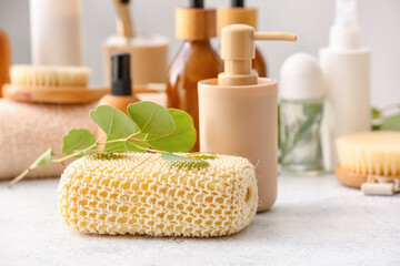 Fototapeta na wymiar Bath sponge, eucalyptus branch and bottles of cosmetic products on light table