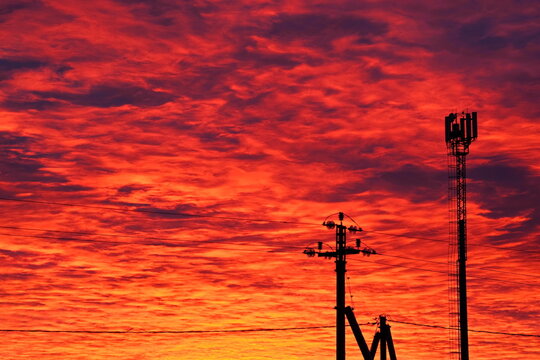 bright red clouds in the sky at sunset and silhouettes of pillars and towers