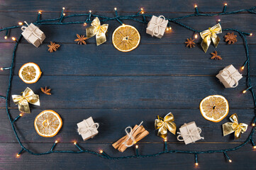 christmas New Year decoration, garland frame , gift boxes, dry orange slices and cinnamon stick yellow bows on a wooden background top view.