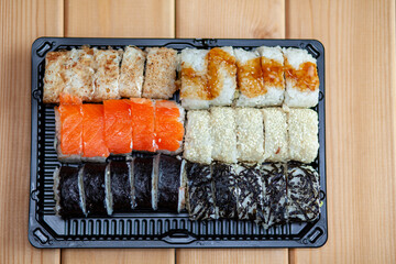 Making sushi and rolls at home. Sushi with seafood, salad and white rice. Food for family and friends. A set of different rolls and sushi on a tray.