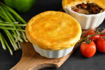 Tasty vegetable pot pies on black background