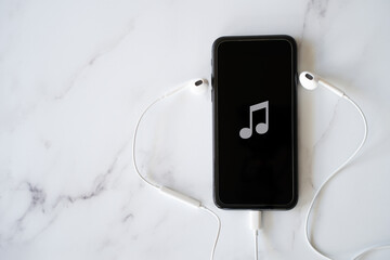 Obraz premium Mobile Phone with Music Note on Screen and Headphones - Concept Music on Your Phone with Copy Space