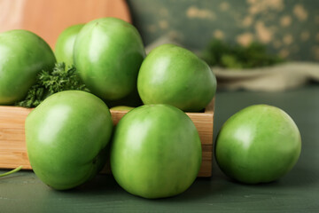 Wooden box with fresh green tomatoes on table, closeup