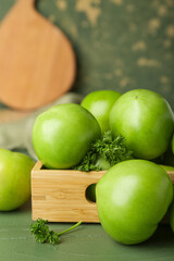 Wooden box with fresh green tomatoes on table, closeup