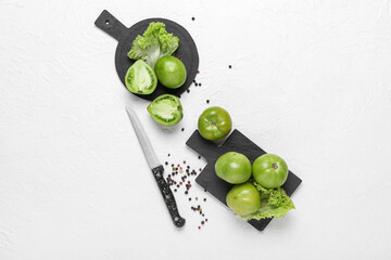 Boards with fresh green tomatoes on white background
