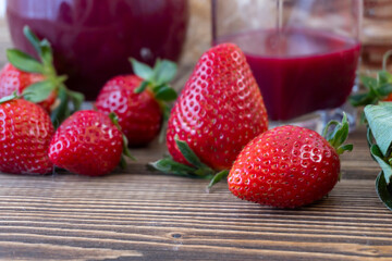 Strawberry in basket and on table on wooden background, strawberry juice in jug