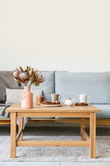 Table with bakery and cups near sofa in living room