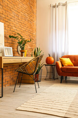 Modern workplace with laptop, pumpkin and sofa in room