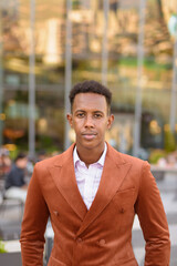 Portrait of handsome black African businessman outdoors in city