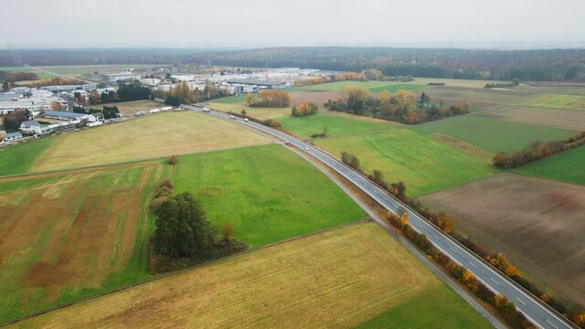 Cinematic aerial, cars driving on single road, through farm fields next to small town, Europe, Germany, Dietzenbach, cinematic 4K