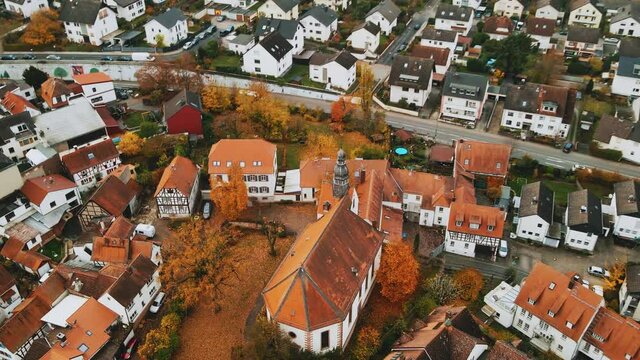 Aerial, beautiful community church with red roof. Rural town in Germany, Europe. Evangelische Christus-Kirche Dietzenbach, cinematic 4K