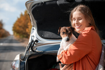 Beautiful woman with cute Jack Russel terrier near car on autumn day