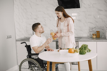 Wife encourage disabled husband sitting in wheelchair at kitchen table