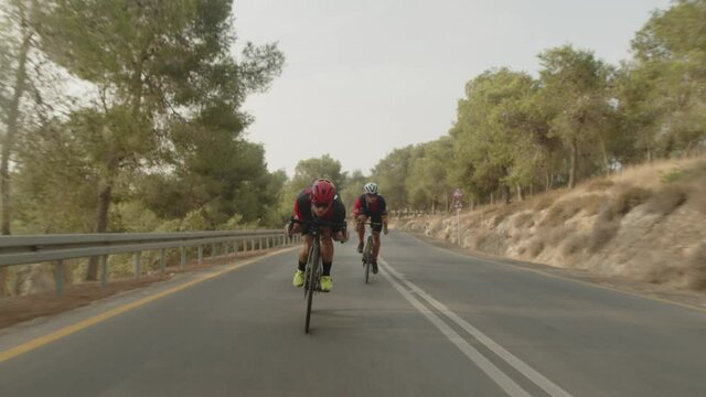 slow motion of two road cycelist professionals riding in the desert's empty road trying to gain more speed