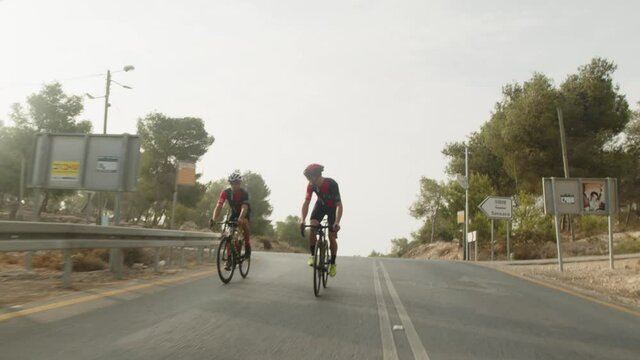 slow motion of two road cycelist professionals riding in the forest's empty road.