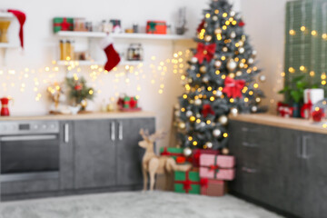 Blurred view of modern kitchen with Christmas tree, gifts and glowing garland