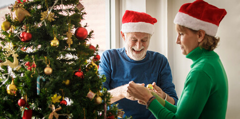 Man and woman decorating Christmas tree with baubles