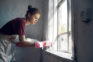 woman painter paints window with brush renovation interior decoration