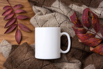 White coffee mug mockup with knitted blanket and red fall leaves