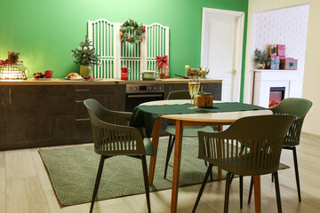 Dining table with glasses of champagne and gift in kitchen decorated for Christmas