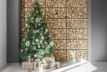 Beautiful Christmas tree with gifts near wooden wall