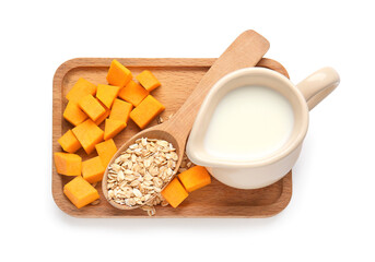 Spoon with oatmeal flakes, jug of milk and pumpkin pieces on white background