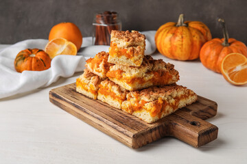 Wooden board with pieces of tasty pumpkin pie on table