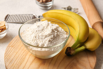 Bowl with flour and bananas for preparing homemade cookies on light background