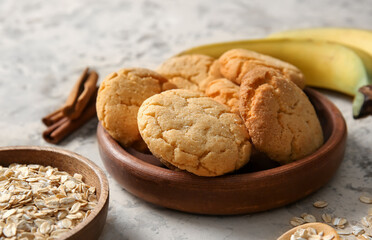Bowl with tasty homemade oatmeal cookies on beige background