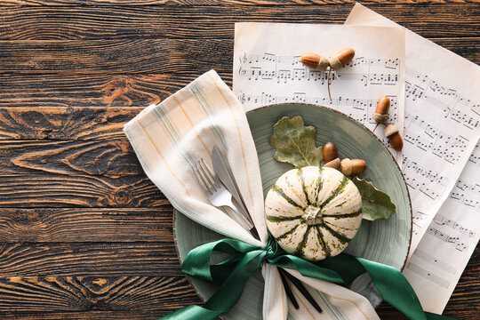 Composition with table setting, music notes and autumn decor on wooden background