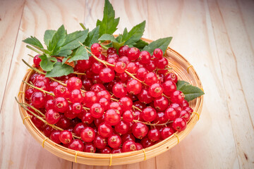 Table top view bunch of red currant in basket, Red currant berries with leaf on wooden table.