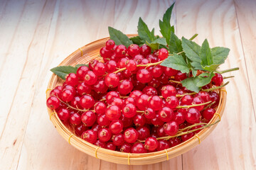 Table top view bunch of red currant in basket, Red currant berries with leaf on wooden table.