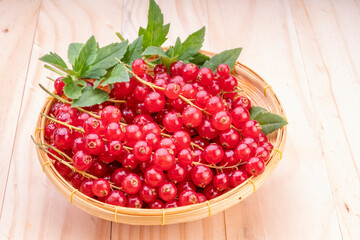 Table top view bunch of red currant in basket, Red currant berries with leaf on wooden table.