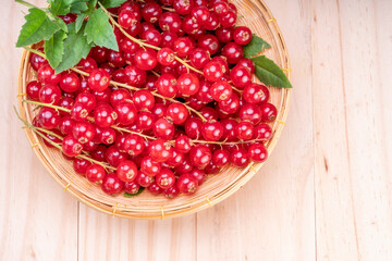 Table top view bunch of red currant in basket, Red currant berries with leaf on wooden table.