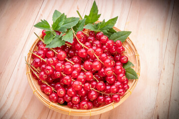 Table top view bunch of red currant in basket, Red currant berries with leaf on wooden table.