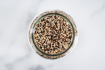 quinoa in clear pantry jar on marble background, simple ingredients concept