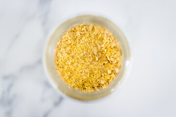 nutritional yeast in clear pantry jar on marble background, simple ingredients concept